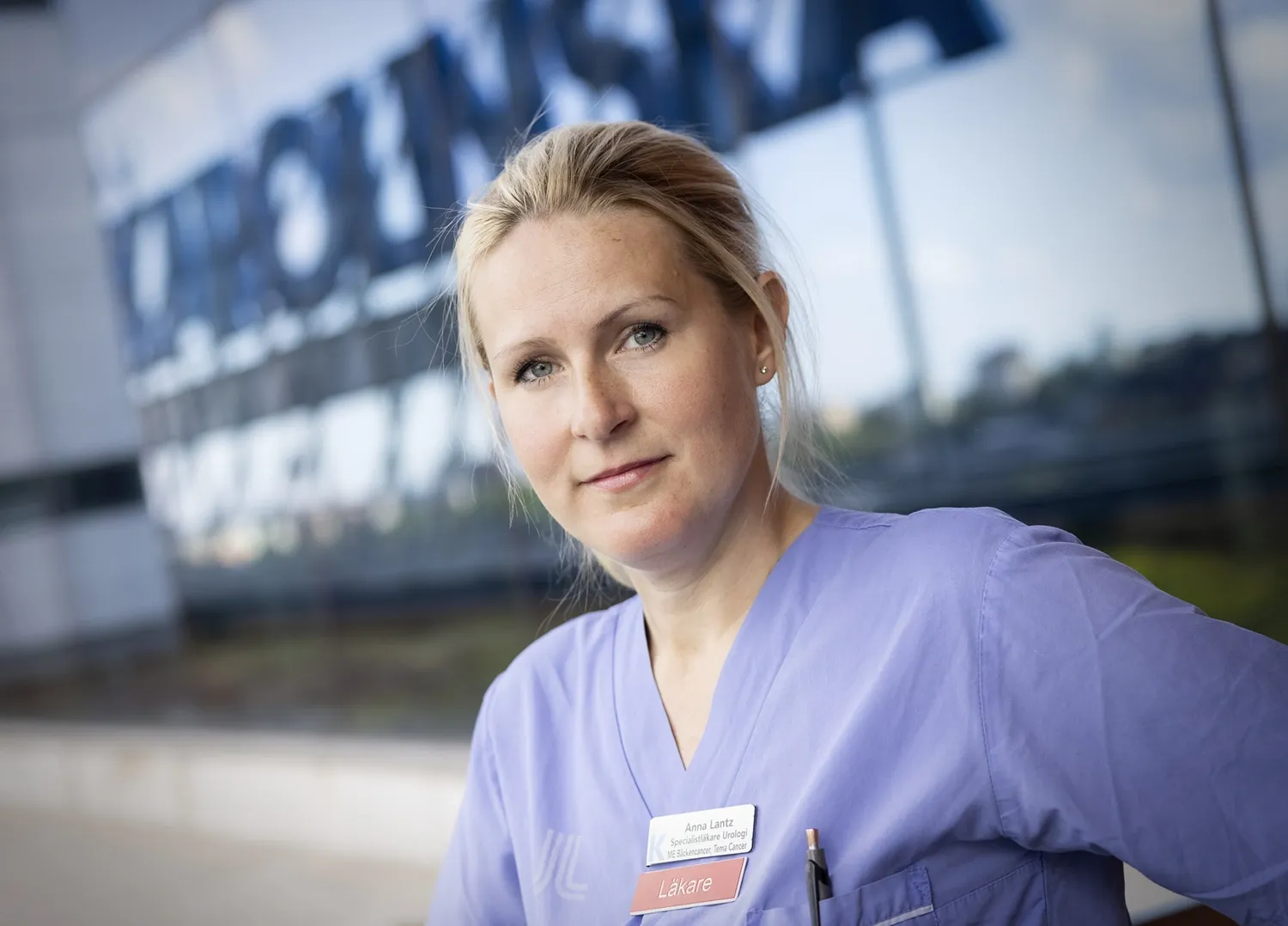 Forskare i läkarekläder framför Karolinskas fasad