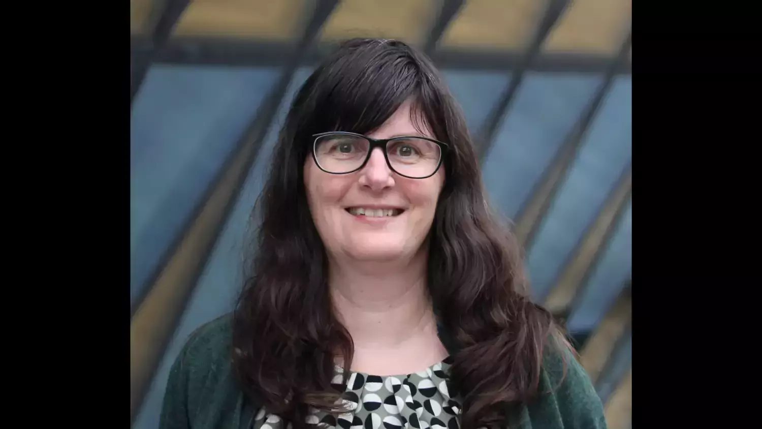 Profilfoto på Anna Zorzet. En kvinna med långt brunt hår, svart kavaj och mönstrad topp