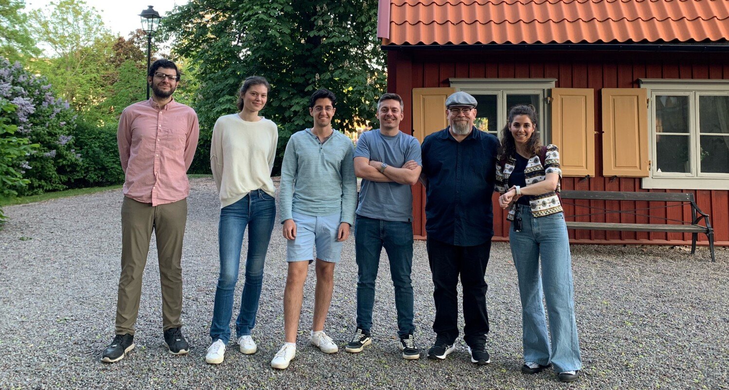 Gruppmedlemmar i forskargruppen Hermanson Laboratory, står samlade utomhus framför ett gult trähus