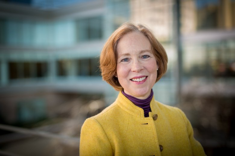 Porträtt av Cynthia Bulik, hon har kort rött hår och gul kavaj.