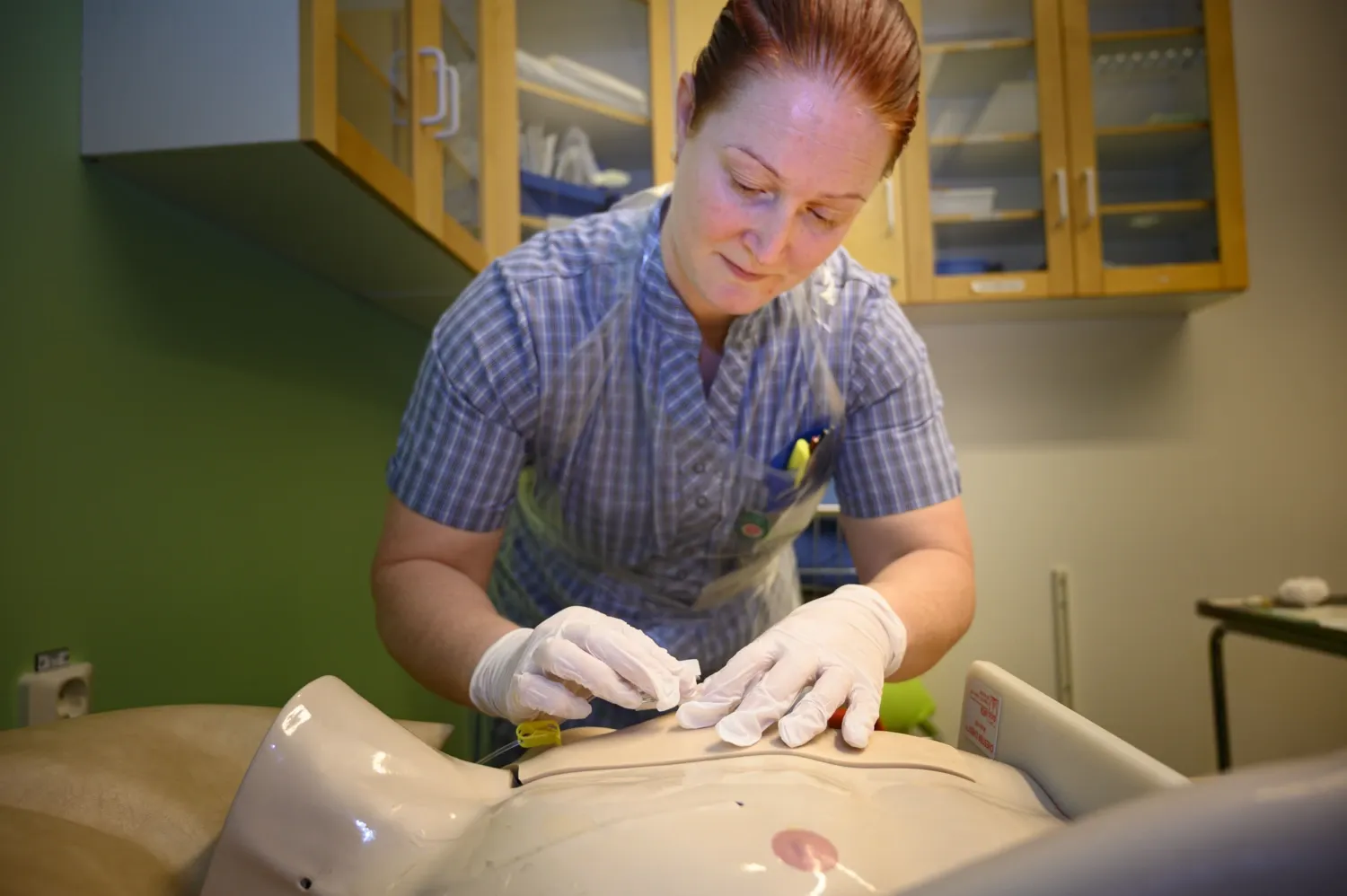 Sjuksköterskestudent vid Kliniskt Träningscenter, ska sticka en provdocka
