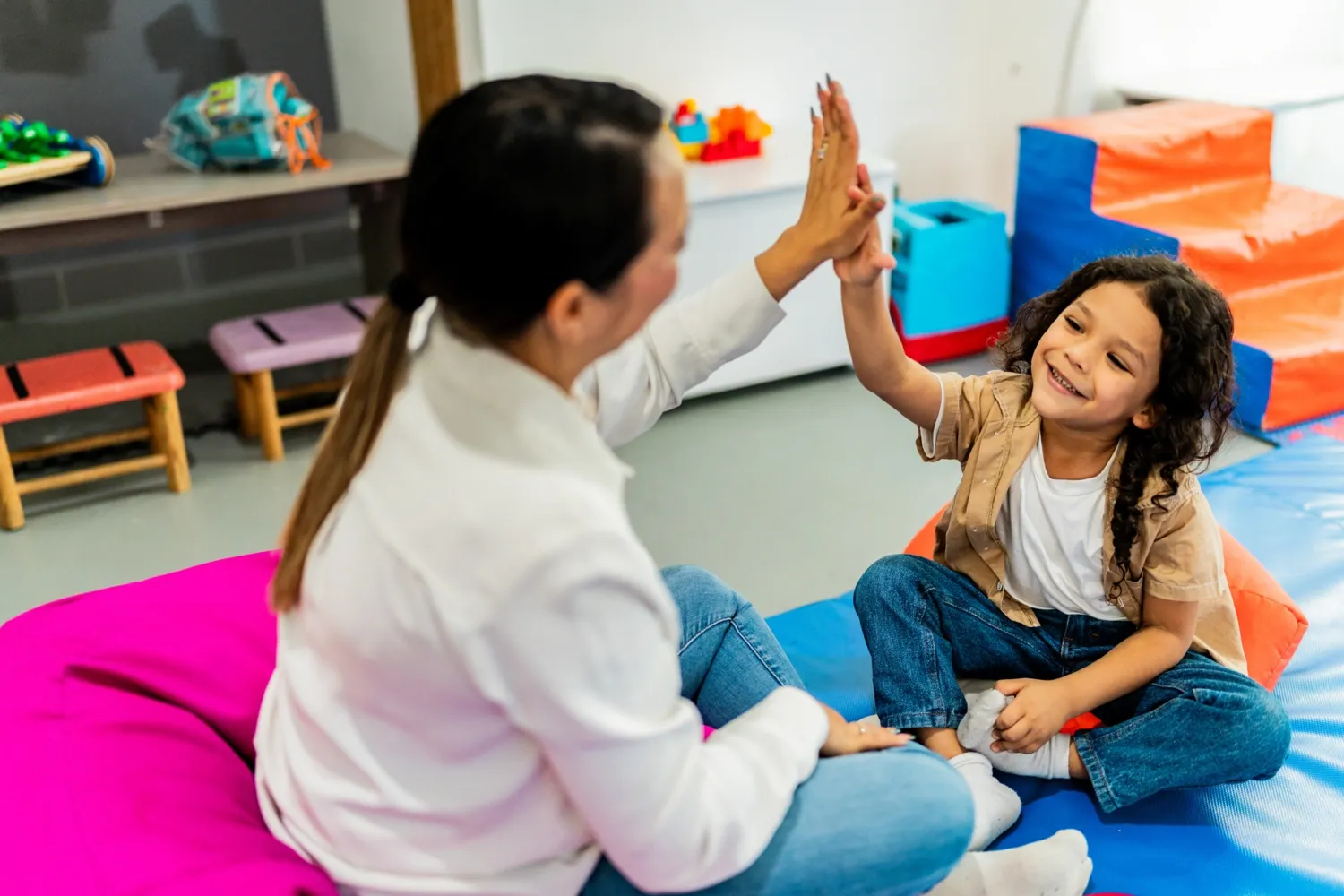 Mid adult psychotherapist woman celebrating with high-five with child boy