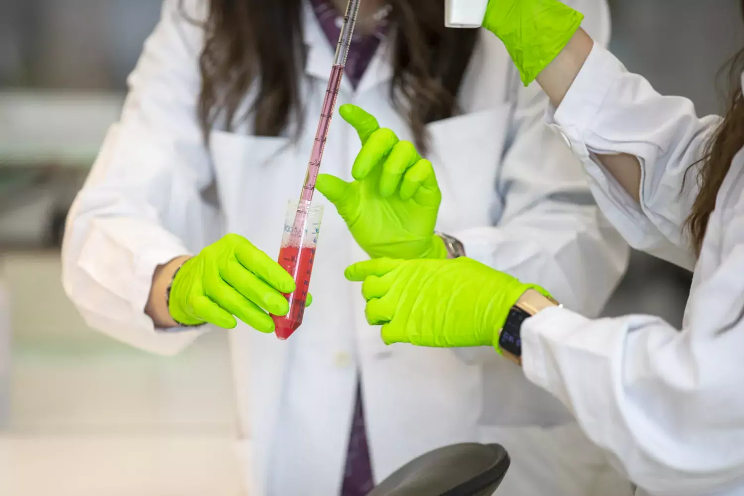Hands working with pipette and test tubes.