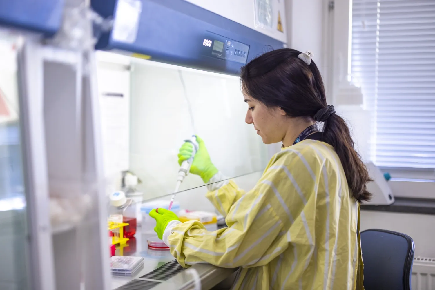 Woman in lab environment working with a pipette.