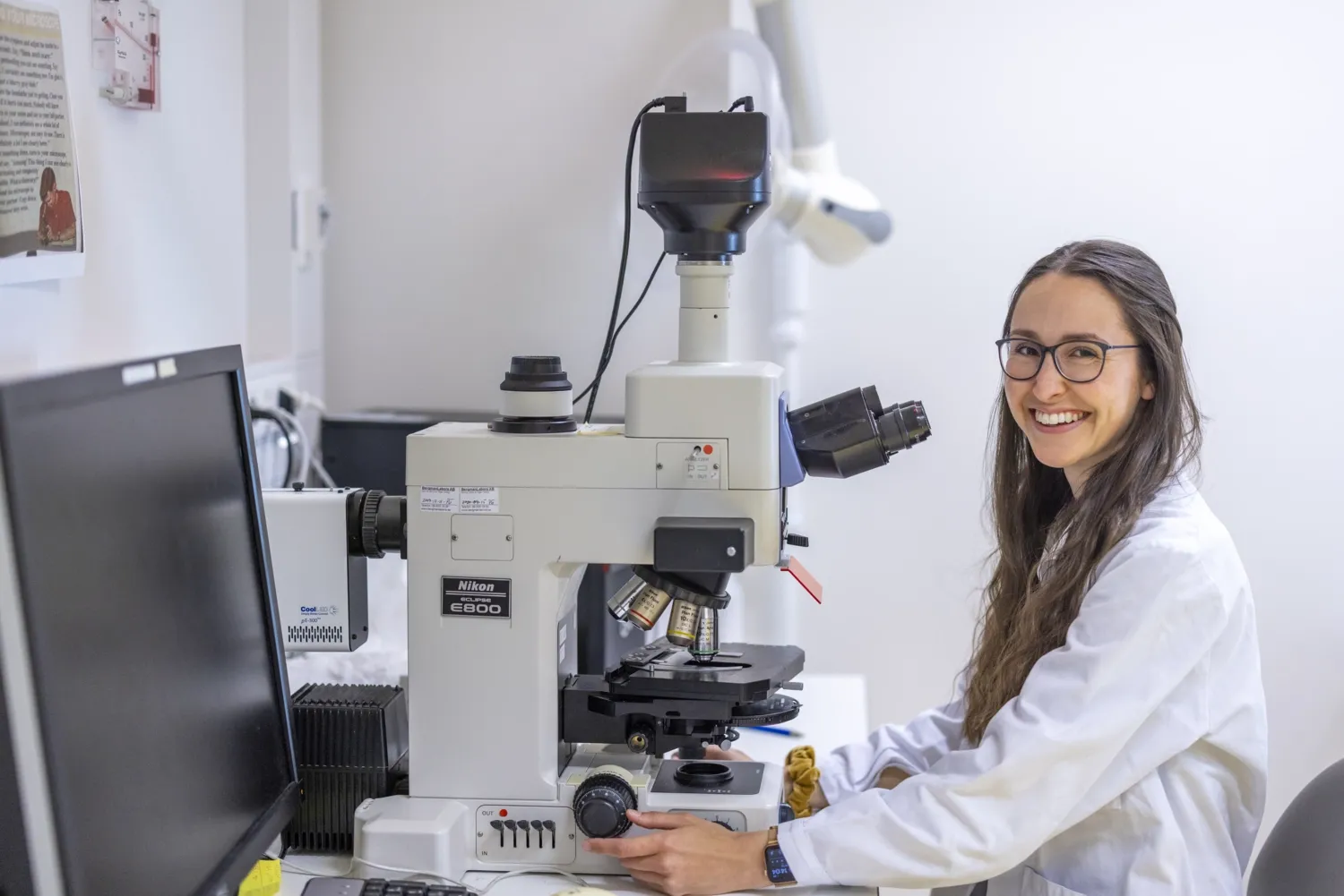 Woman looking up in to the camera from a microscope.