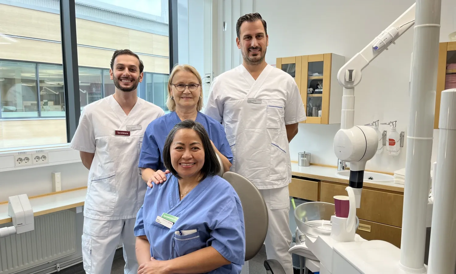 två tandläkare och två tandsköterskor i ett behandlingsrum för tandläkare