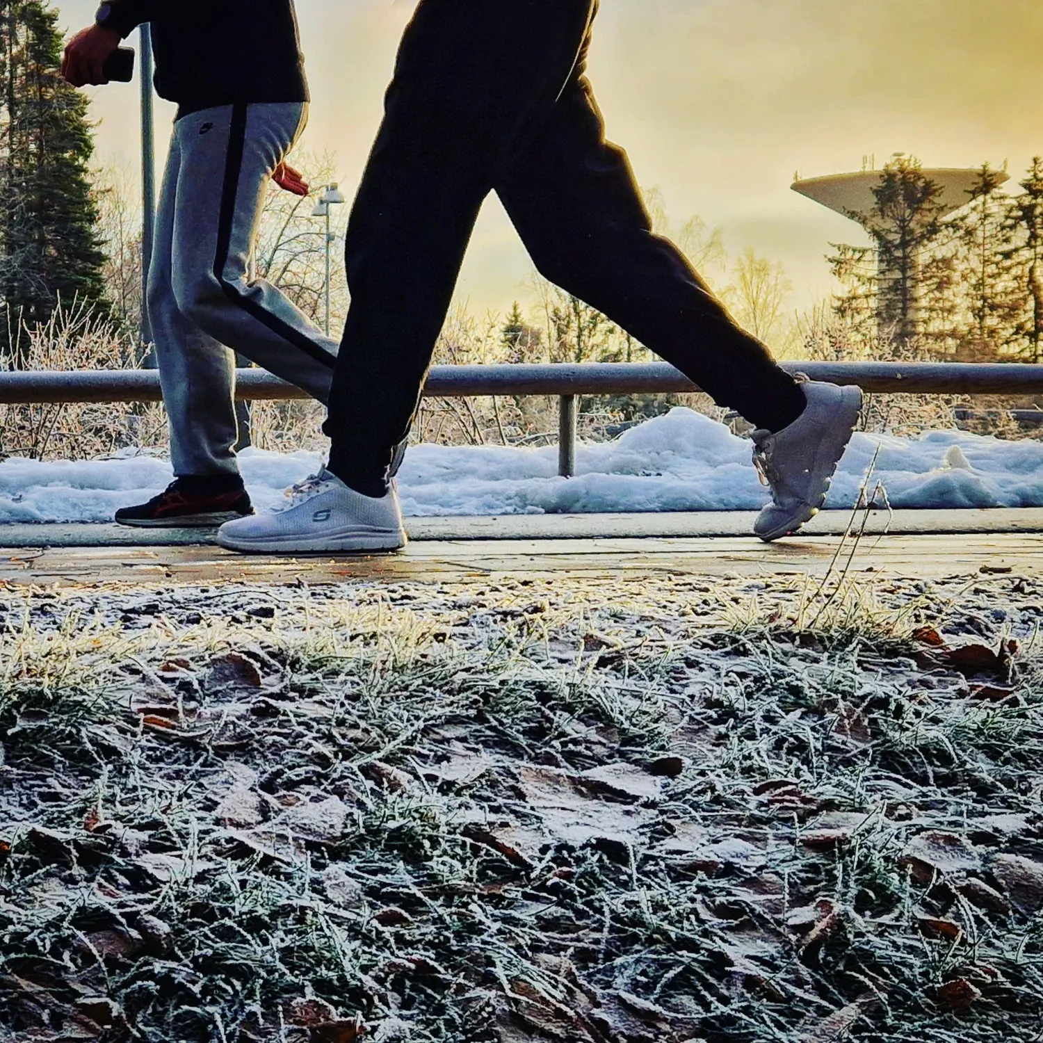 Två par ben som går. Vattentorn i bakgrunden.