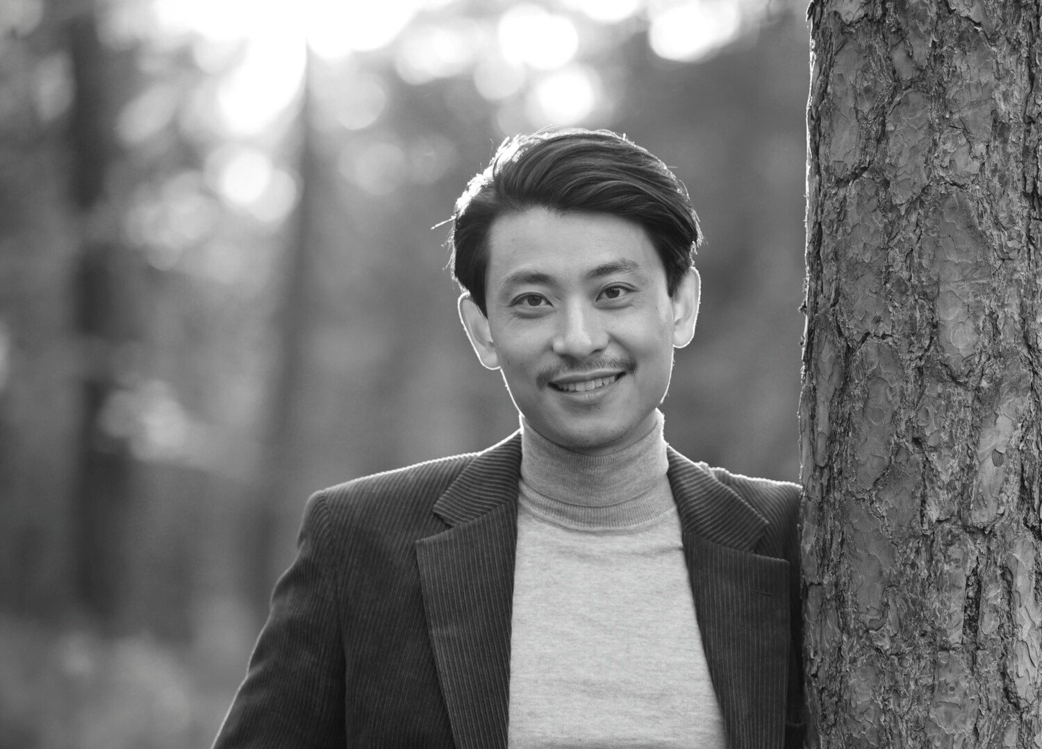 Svartvitt fotografi av leende man i kavaj.