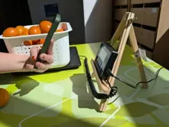 A basket of fruit. Next to it, a stand with electronic equipment that a person scans with their mobile phone.