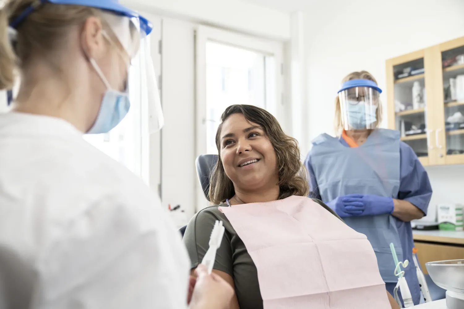 Dental treatment, patient in the chair with dentist and detnal nurse.