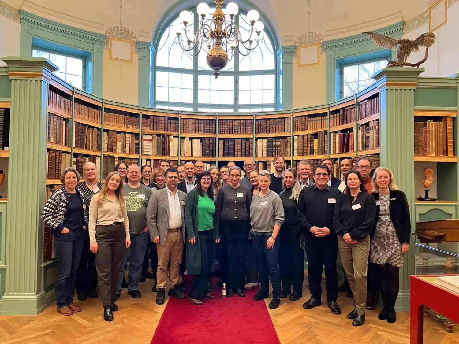 A group of people standing in and in front of a bookcase