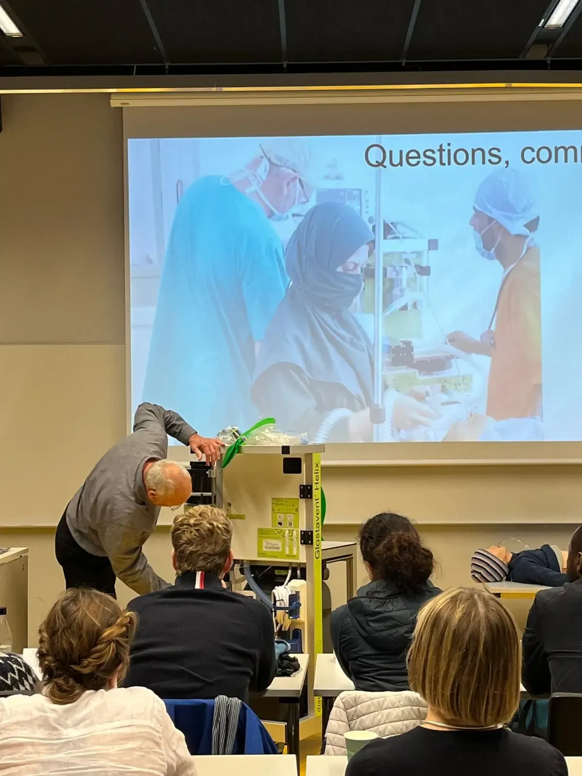 A person standing in front of a class showing a piece of equipment