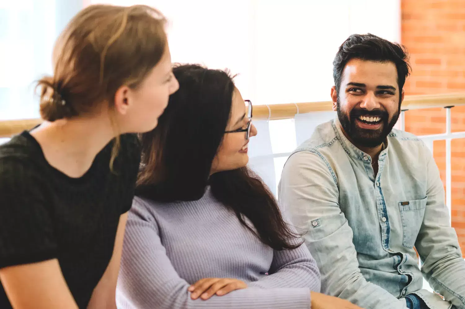 Två kvinnor och en man sitter och pratar med varandra.