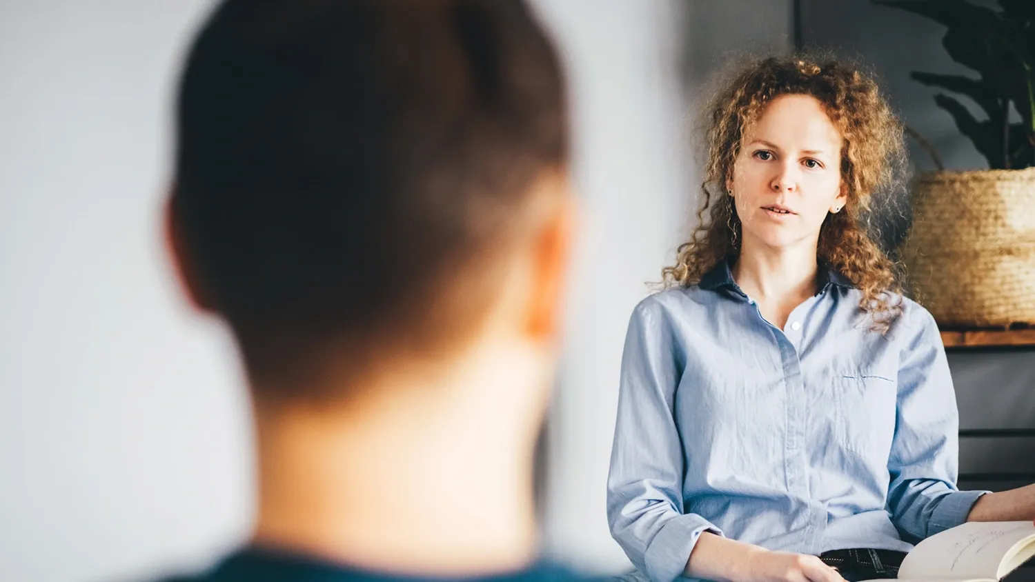 En kvinna i ljus skjorta i fotad framifrån. En mans bakhuvud suddigt i förgrunden.
