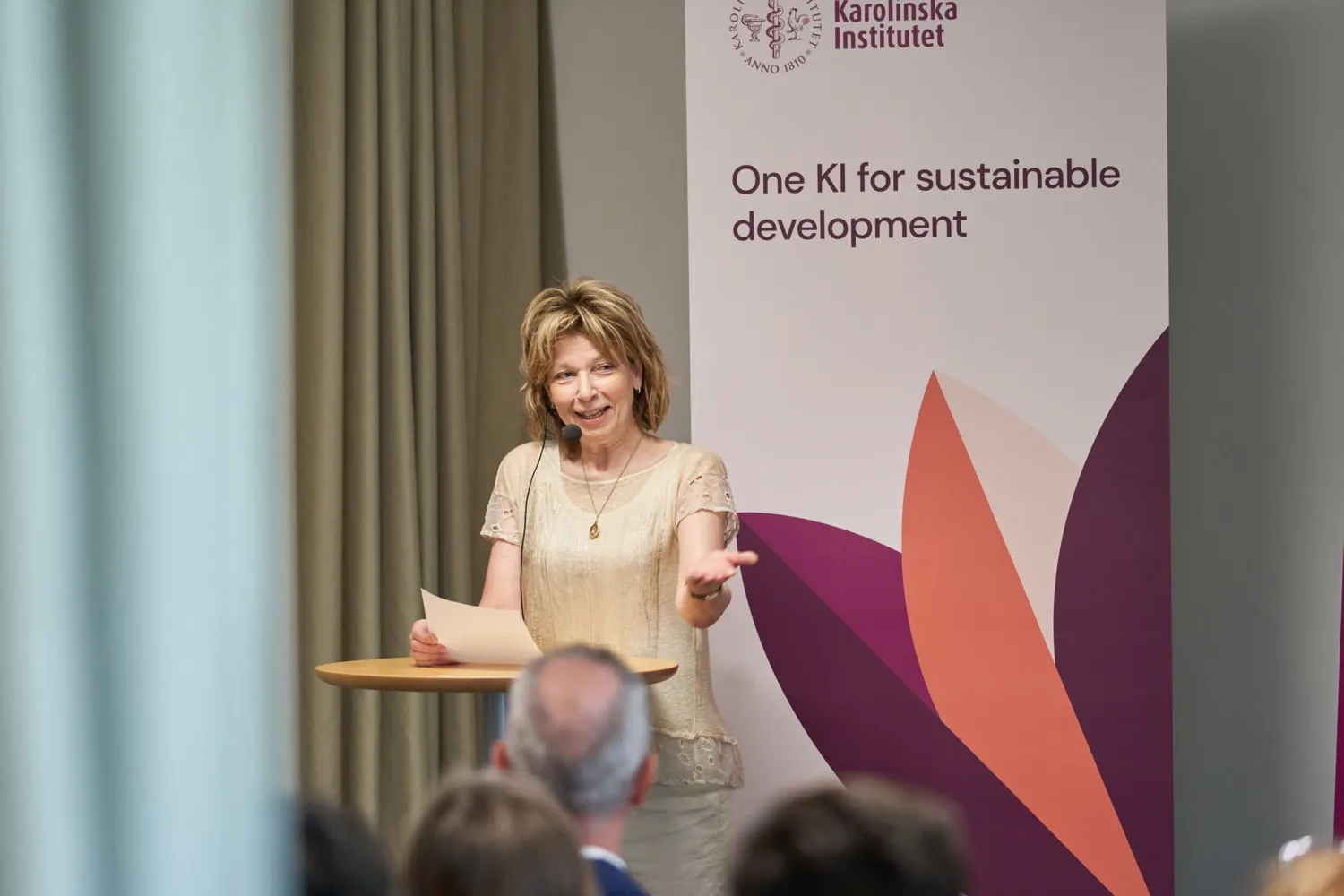 Rektor Annika Östman Wernerson med mikrofon på scen framför skyllt med text One KI for sustainable development