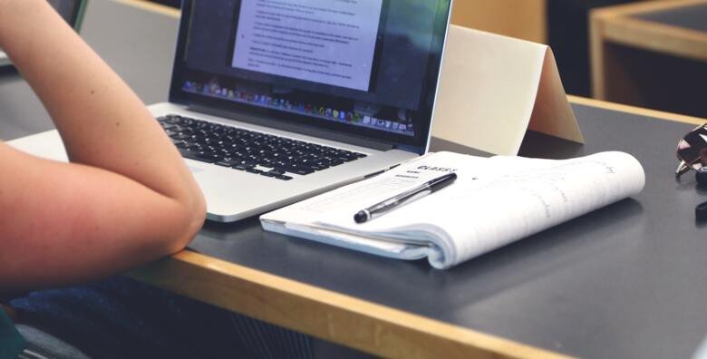 Doktorand på föreläsning med dator och anteckningsblock.