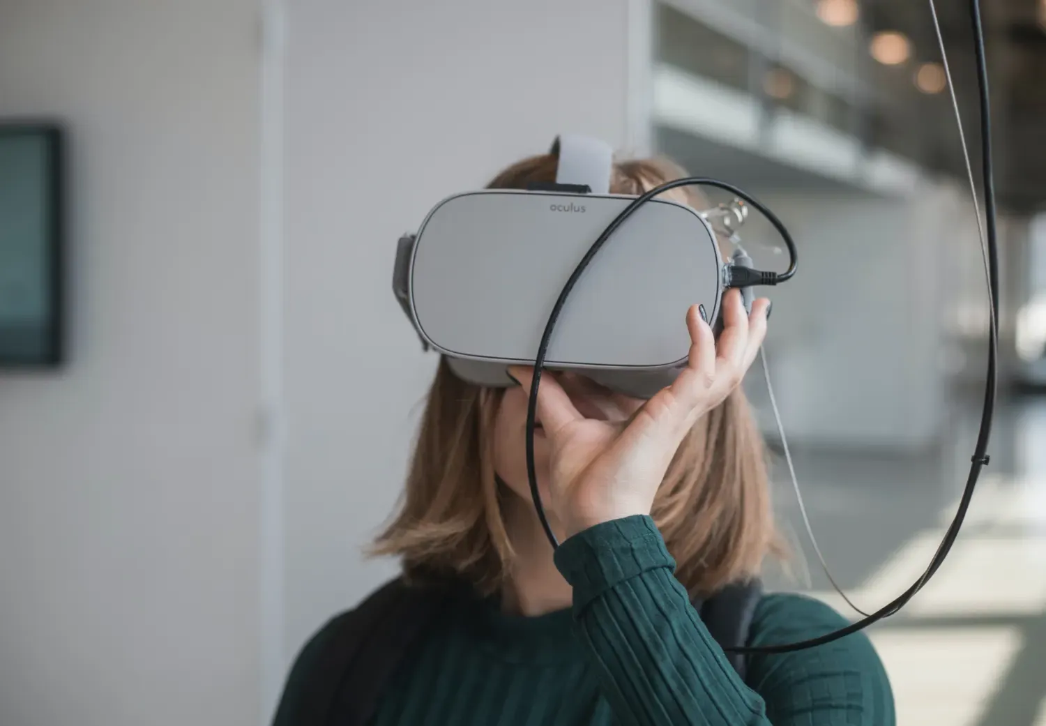 Woman in black sweater holding white and black VR goggles