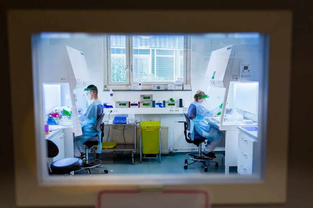 två människor sitter i var sitt dragskåp och arbetar