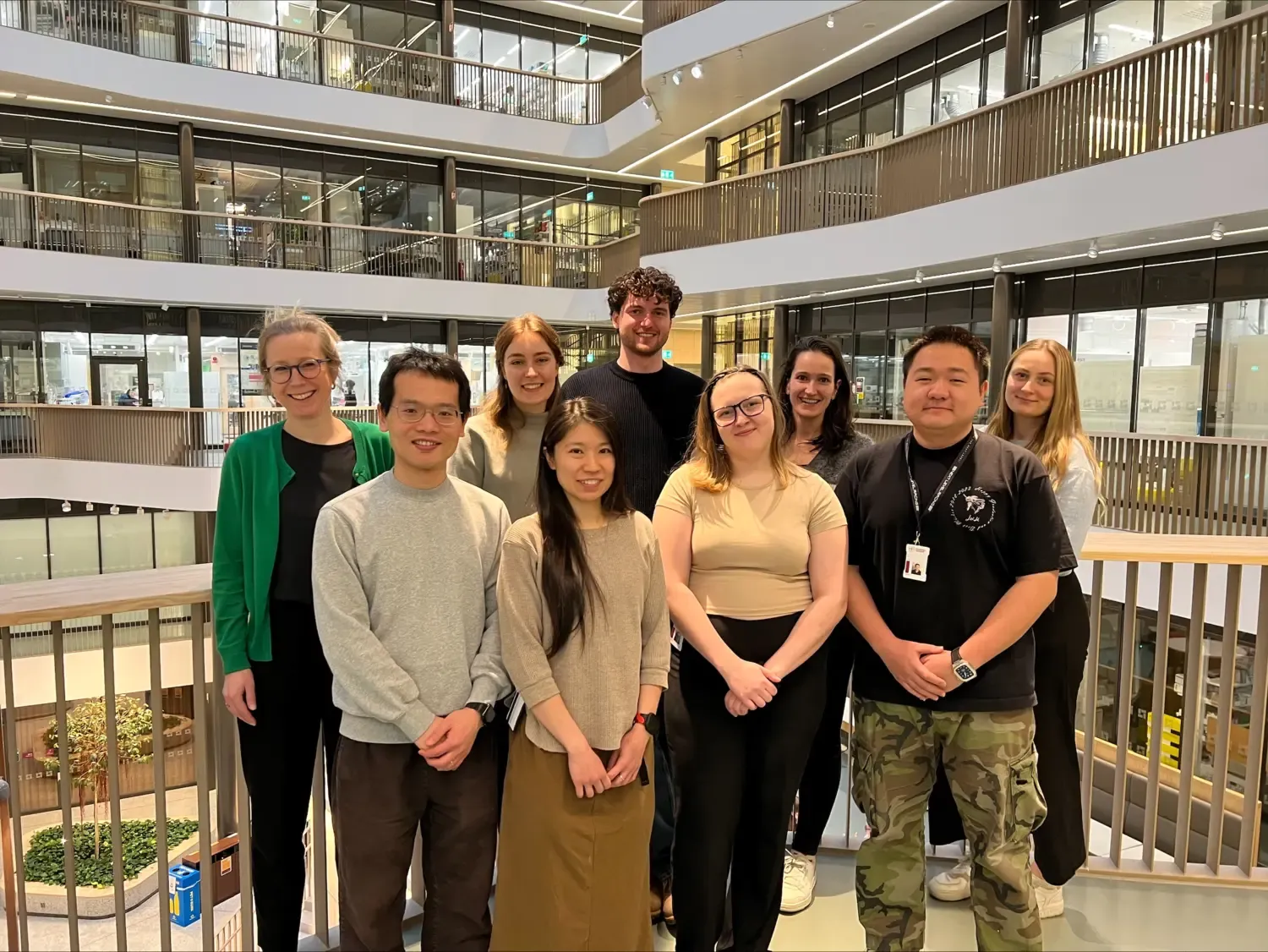 Nine people standing next to each other inside Biomedicum.