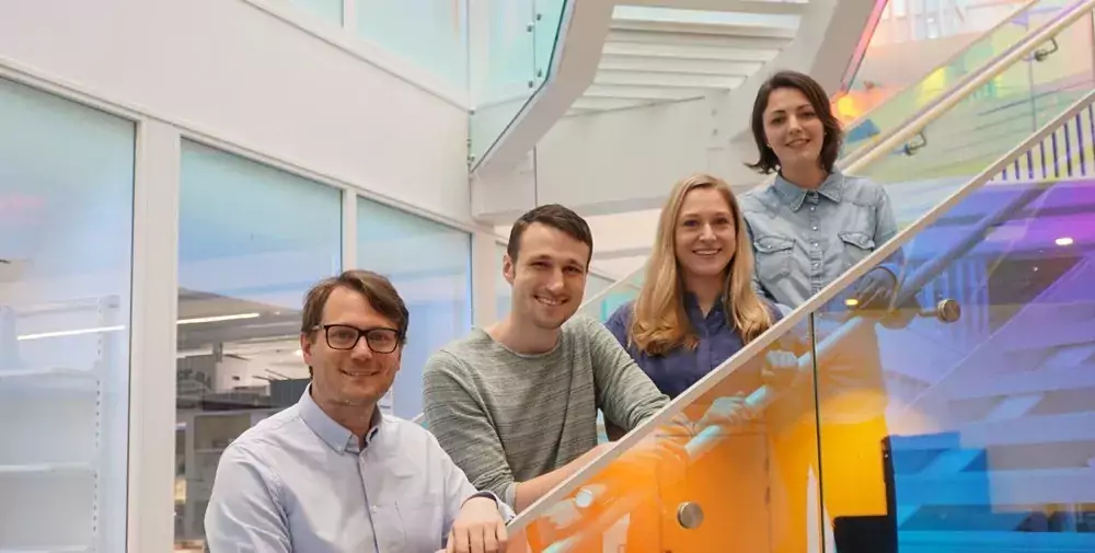 Group picture of four people, standing on a staircase.