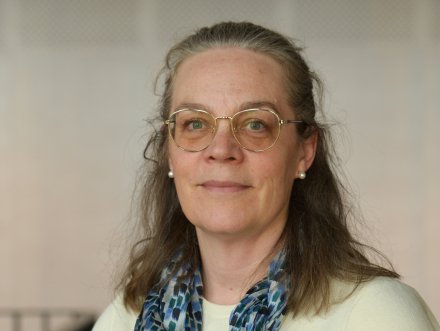 Porträtt av kvinna i vit tröja och halsduk.