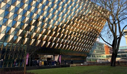 The entrance of Aula Medica. The sun is reflecting in the glass windows. Two flags with the text "Examen" is standing in front of the entrance.