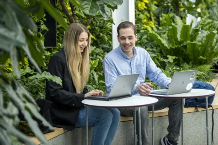 Students revising together at a table in front of a wall of greenery at campus Solna.