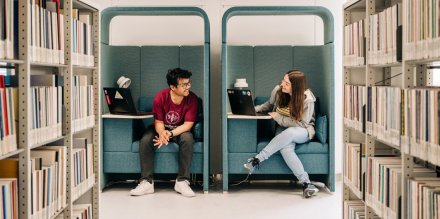Två studenter sittandes i fåtöljer i universitetsbiblioteket i Solna.