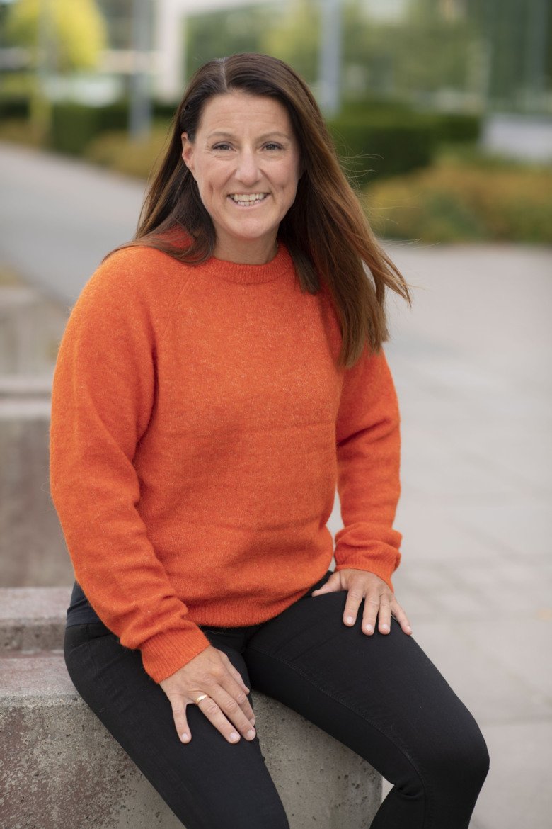 Porträtt av Erika Franzén utomhus. Hon har en orange tröja på sig och långt mellanblont hår.