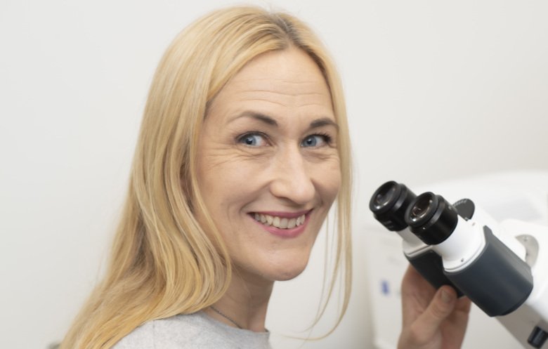 Camilla Svenson in front of a microscope.