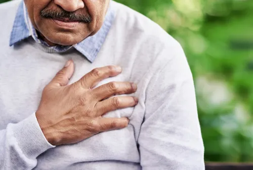 Closeup shot of a mature man holding his chest in discomfort outdoors