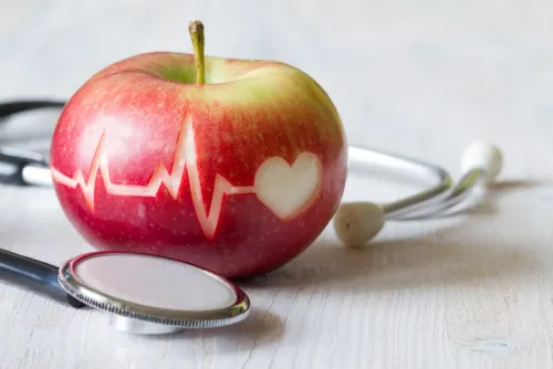 Red apple with a heartbeat (ECG) line and a stethoscope, symbolizing healthy eating and heart health.